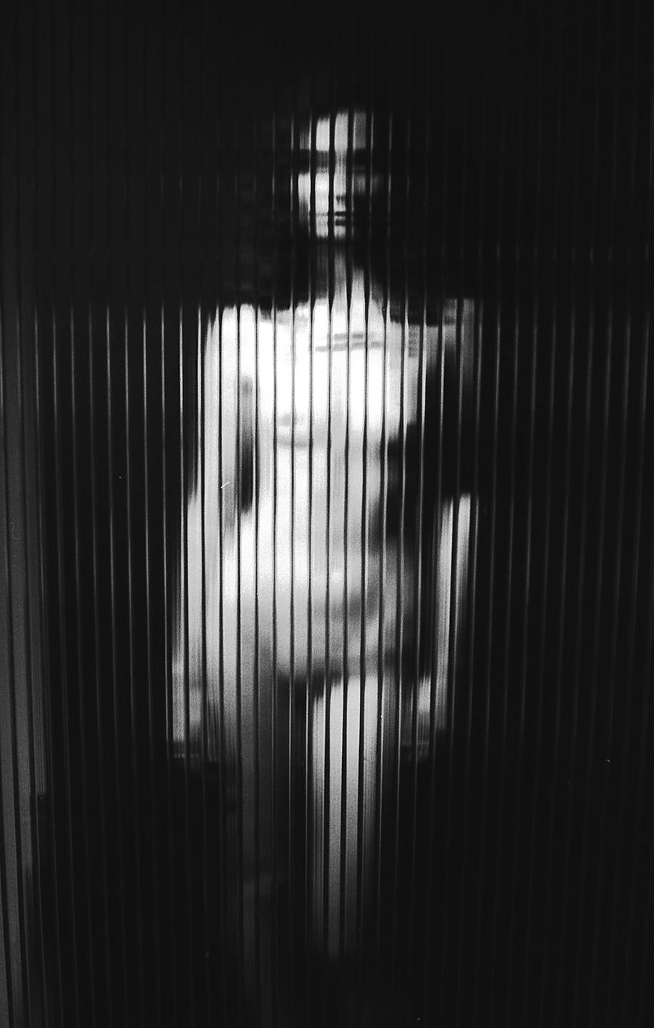 A woman is visible through a translucent corrugated panel.