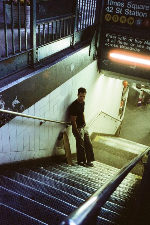 A man stands on a subway staircase next to a sign for Times Square.