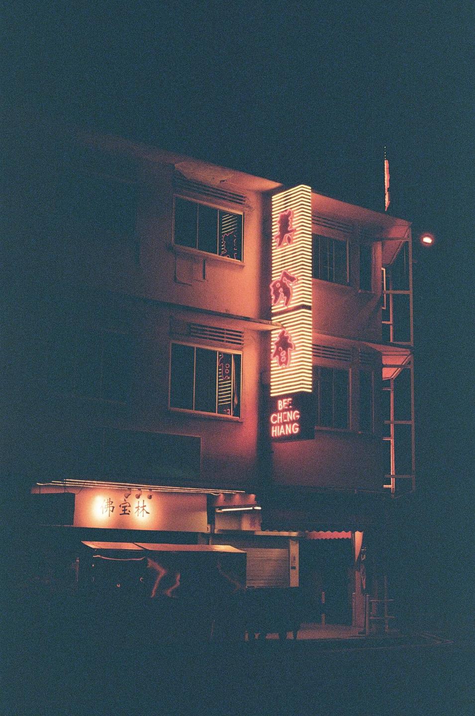A building with glowing red and orange neon signs is visible at night.