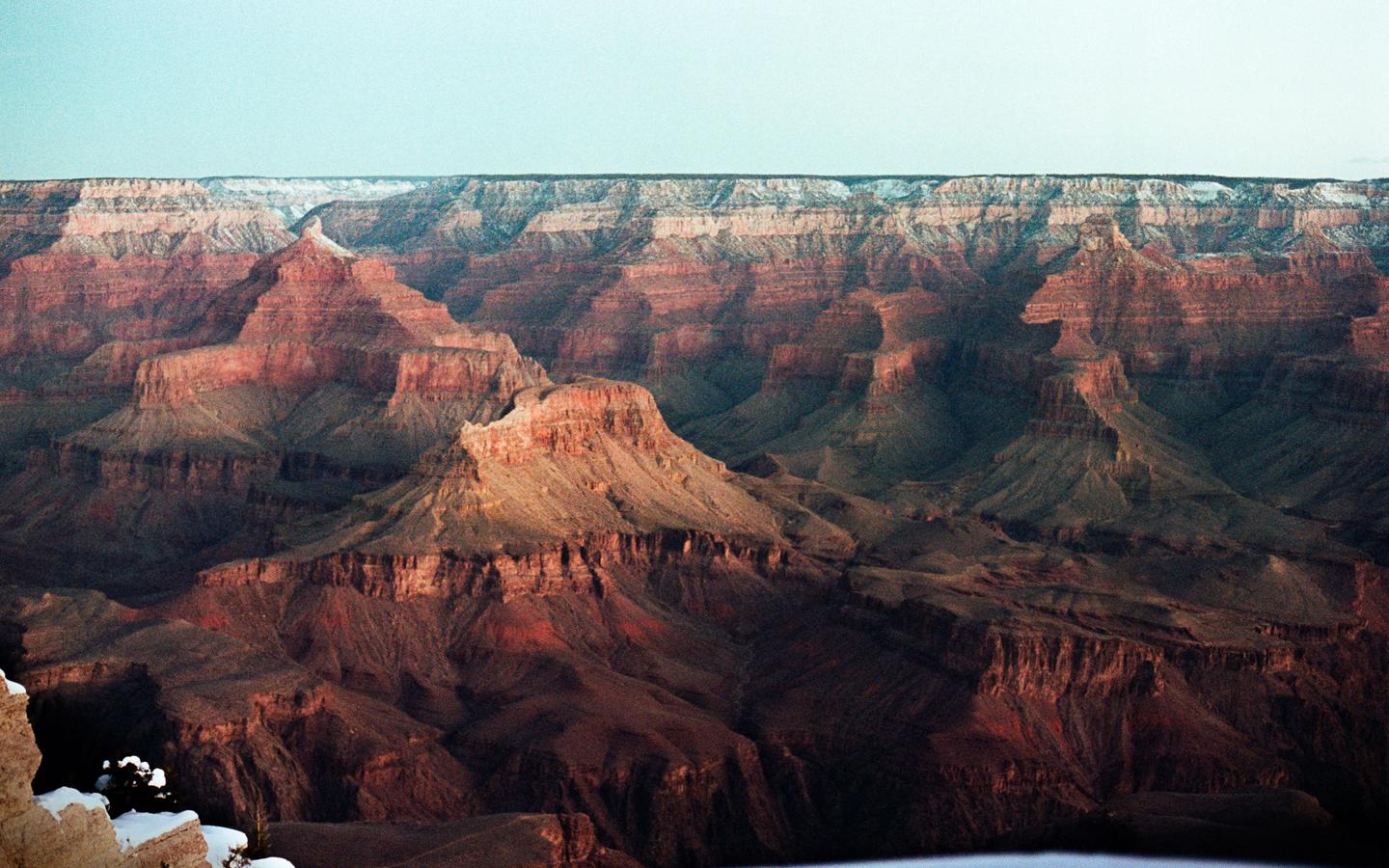 The Grand Canyon is visible with snow on the peaks and a clear sky.