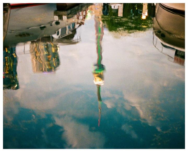 A reflection of a tower and boats is visible in the water.