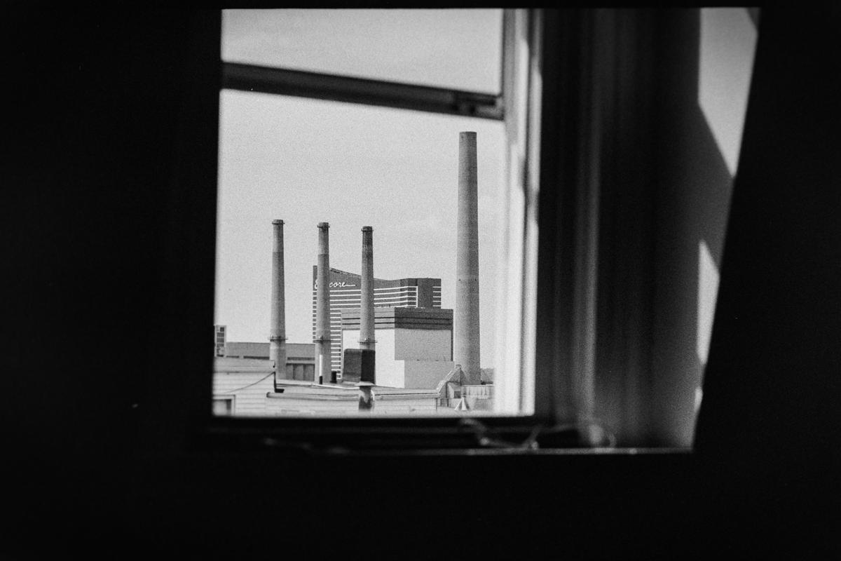 A view of several smokestacks and buildings is visible through a window.