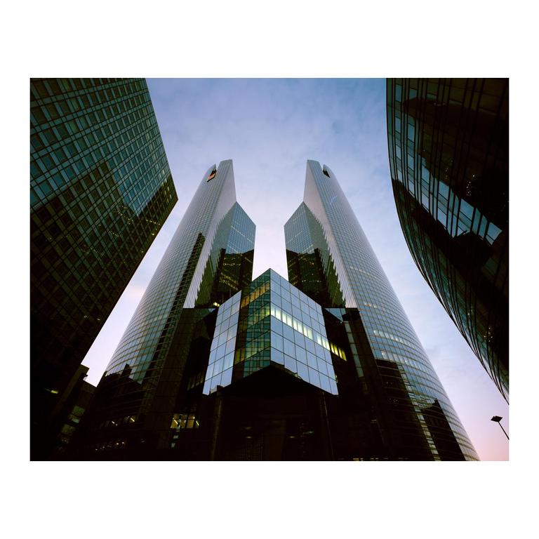 Four glass skyscrapers rise into a pale sky, with two prominent towers in the center.