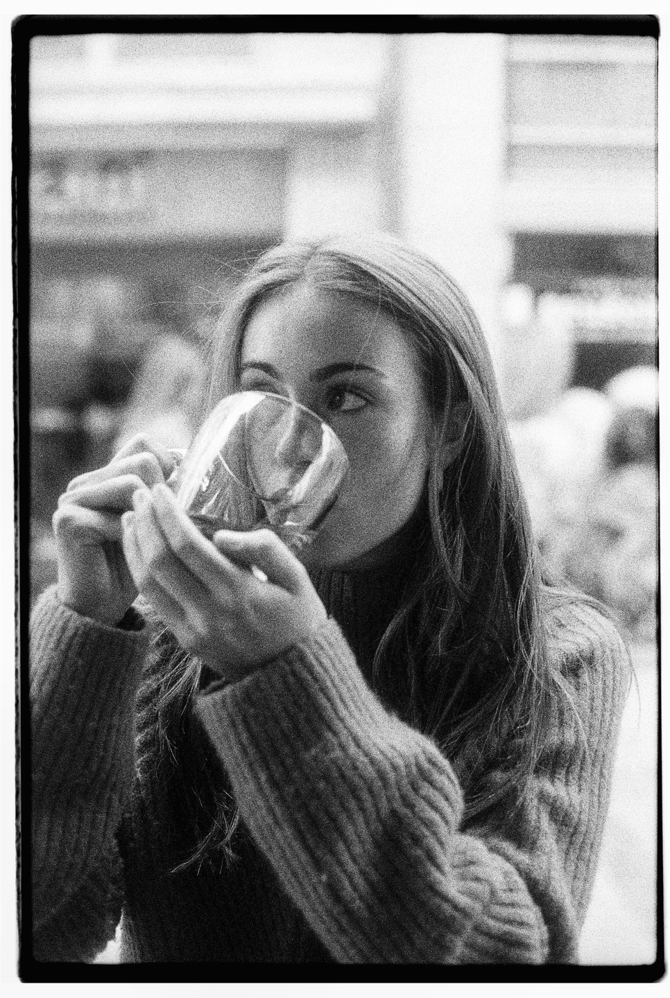 A woman in a sweater drinks from a glass.