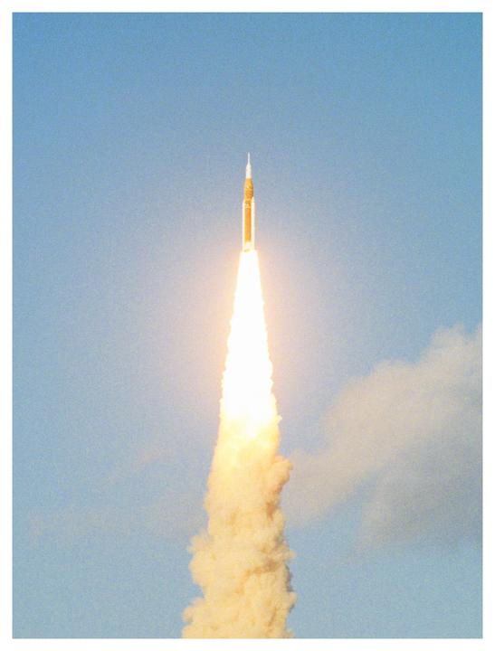 A rocket launches into a clear blue sky, leaving a trail of fire and smoke.