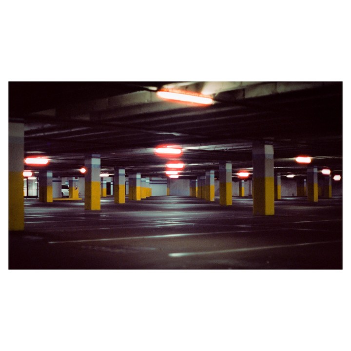 An empty parking garage is illuminated by red lights and yellow pillars.