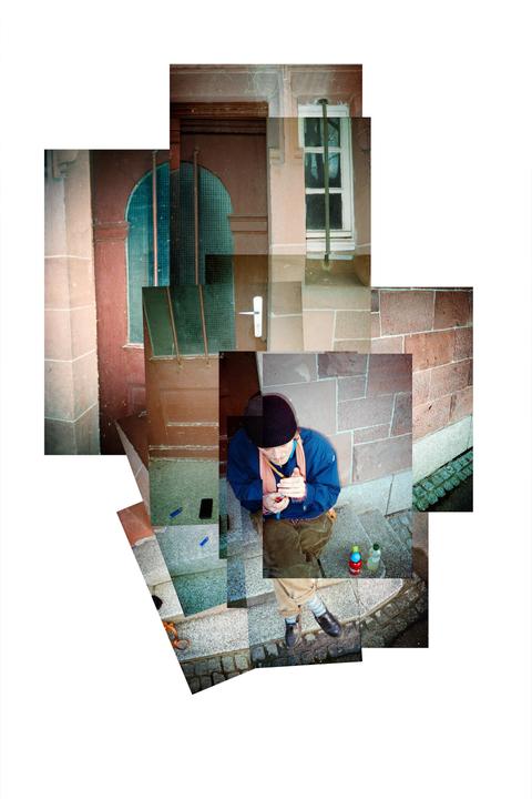 A man sits on stone steps next to a building with a blue door and window.
