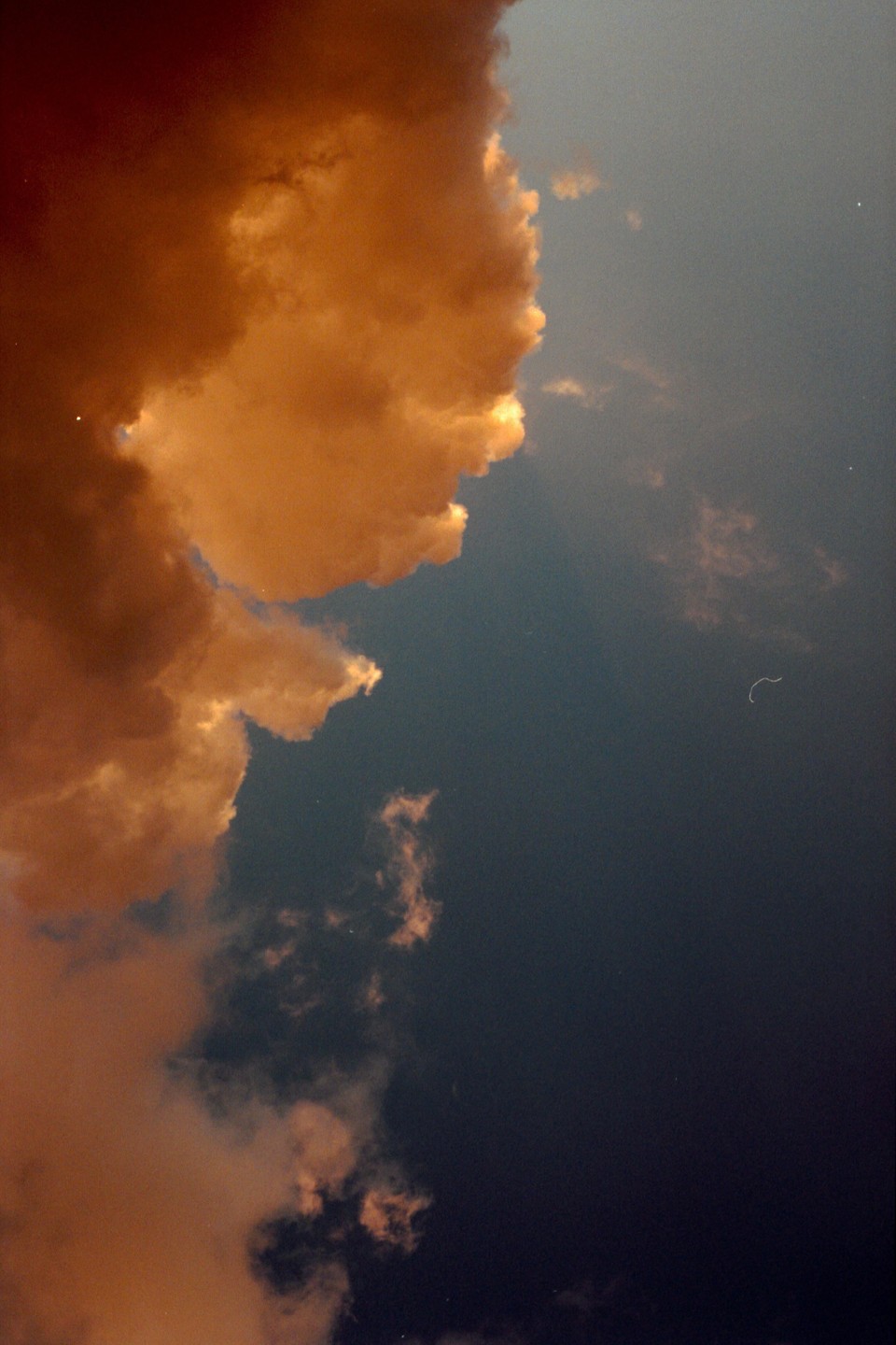 A large, brightly lit cloud fills the left side of the frame, contrasting with the dark blue sky on the right.