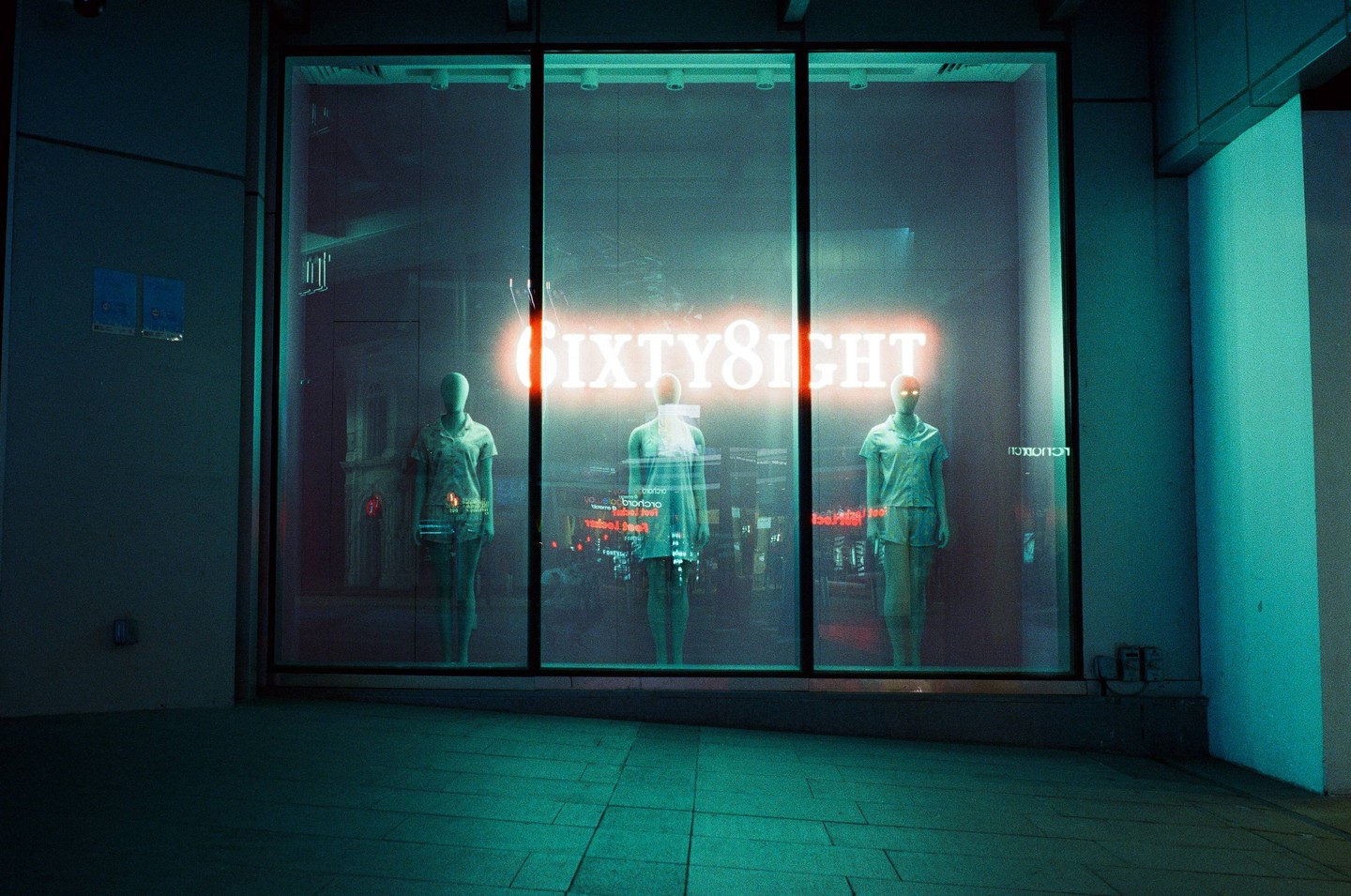 Three mannequins stand in a storefront window with a neon sign that reads "SIXTY8IGHT" above them.