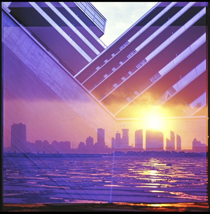 A double exposure shows a cityscape at sunset over a frozen lake, overlaid with a modern building facade.