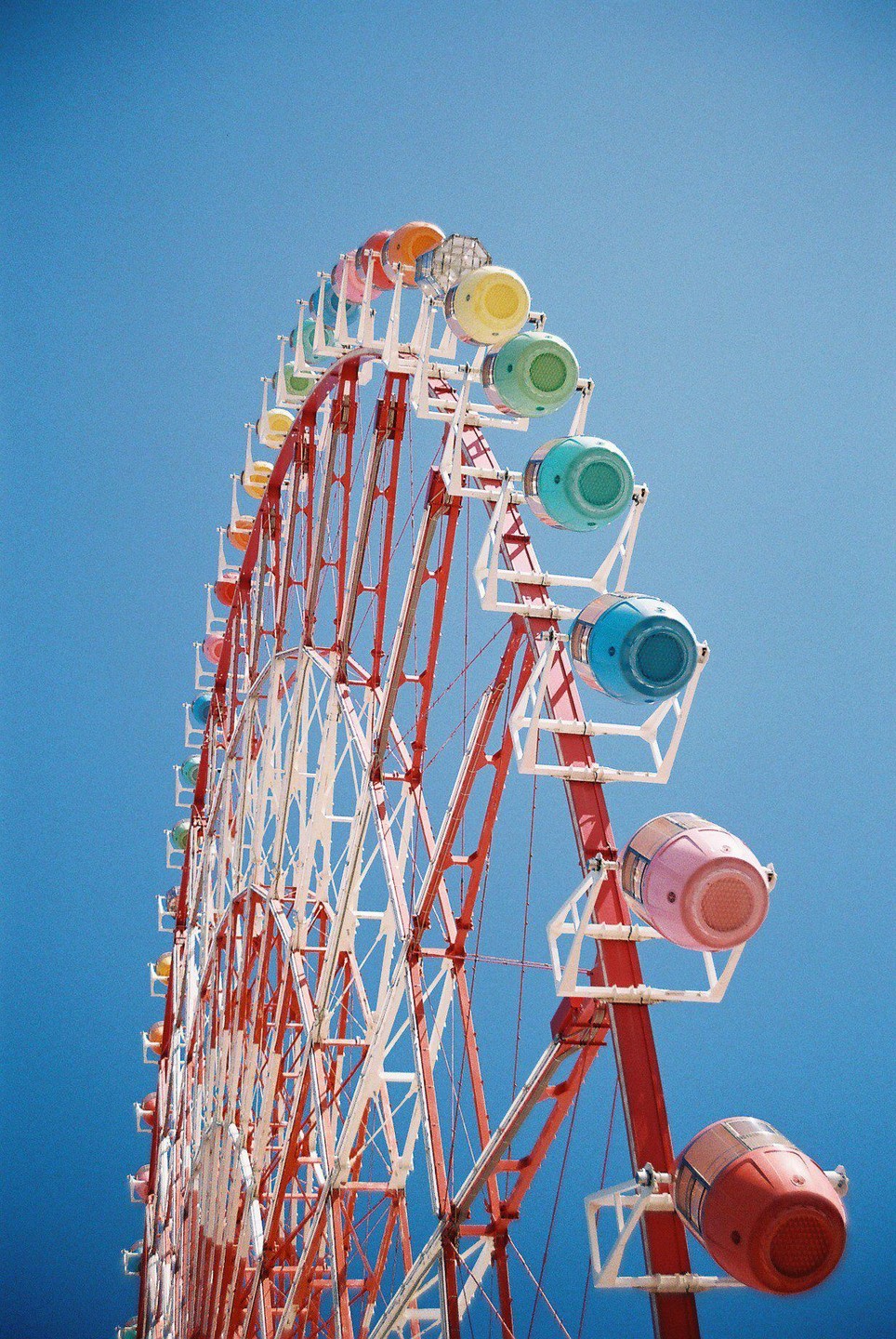 A colorful ferris wheel stands against a clear blue sky.