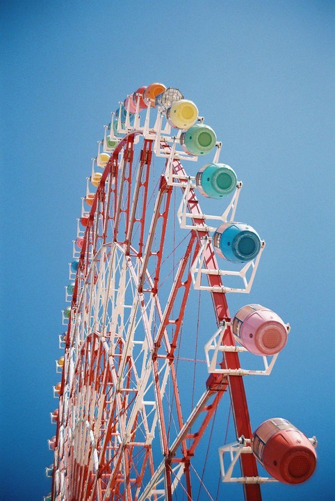 A colorful ferris wheel stands against a clear blue sky.