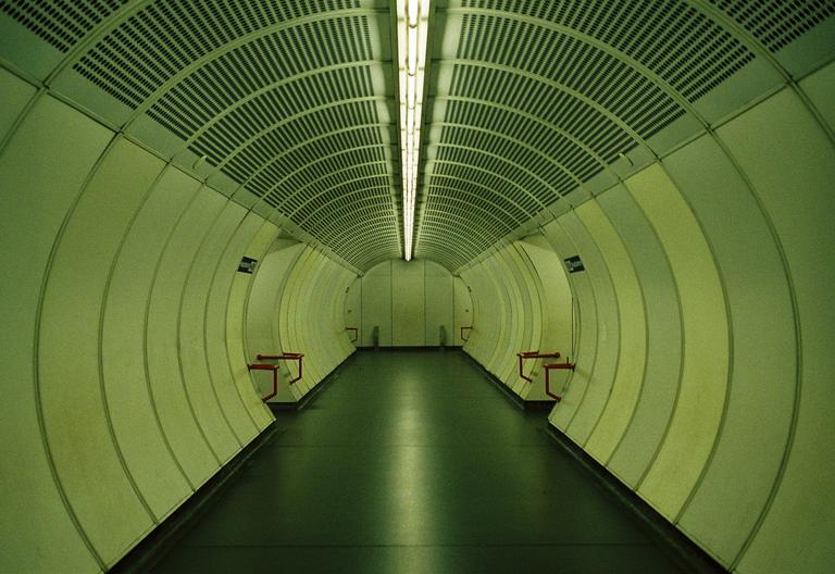 A long, empty, and brightly lit tunnel extends into the distance.