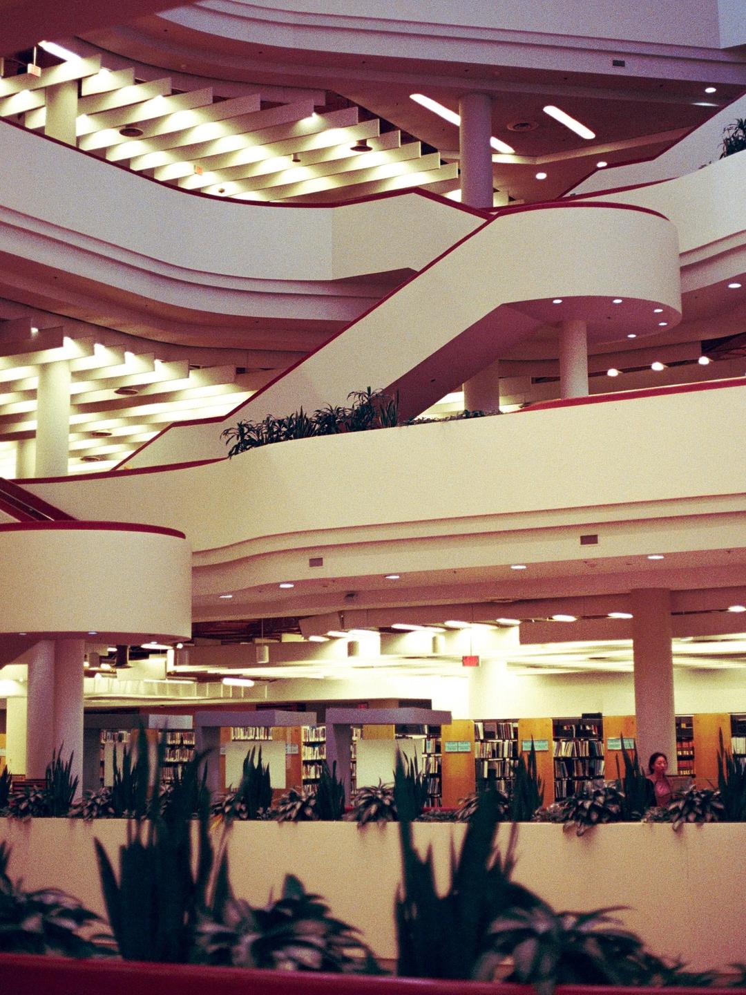 A multi-story library with curved staircases and bookshelves visible on the lower levels.