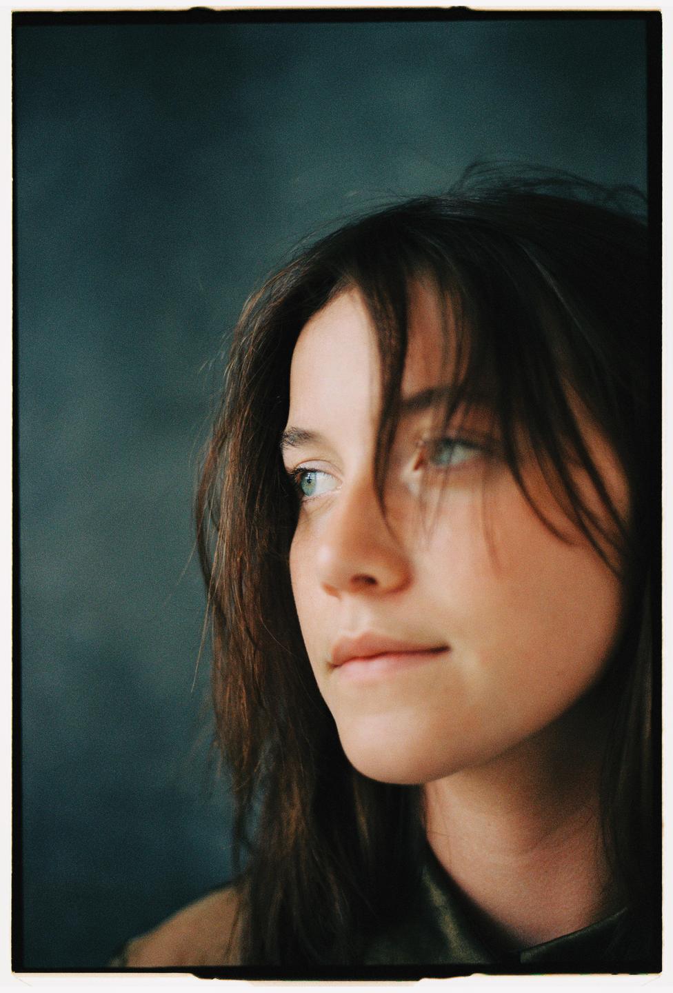 A woman with long hair looks to the right of the frame.