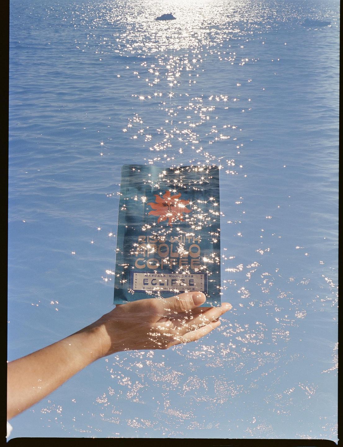 A hand holds a blue package above sparkling water.