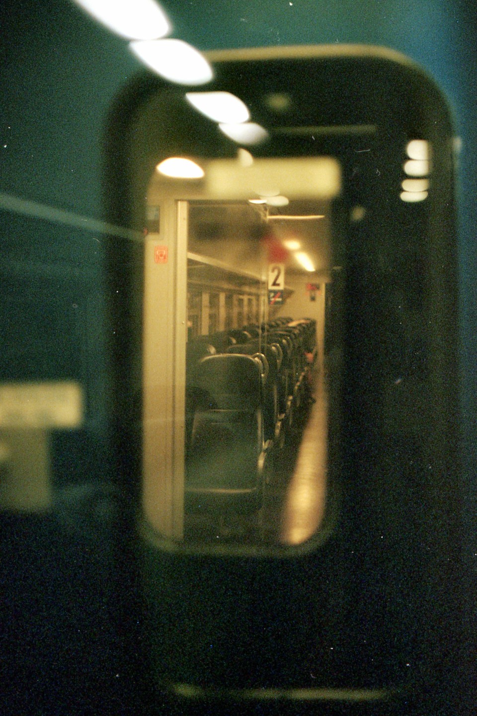The interior of a train car with rows of seats is visible through a window.