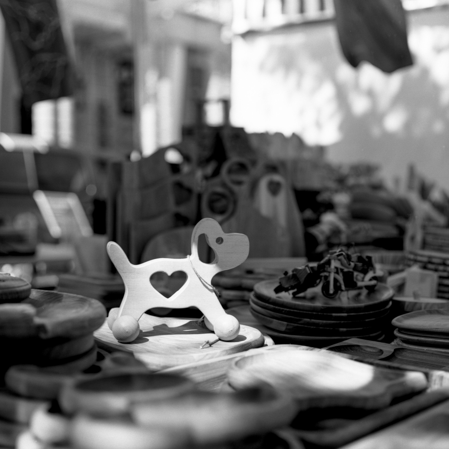 A wooden dog toy with a heart cutout is displayed on a table among other wooden items.
