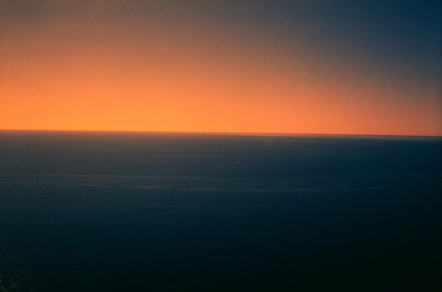 The sun sets over the Ligurian Sea, with a small boat visible in the distance.