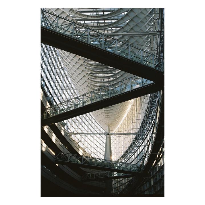 The interior of a modern building features a complex structure of glass, metal beams, and curved white panels.