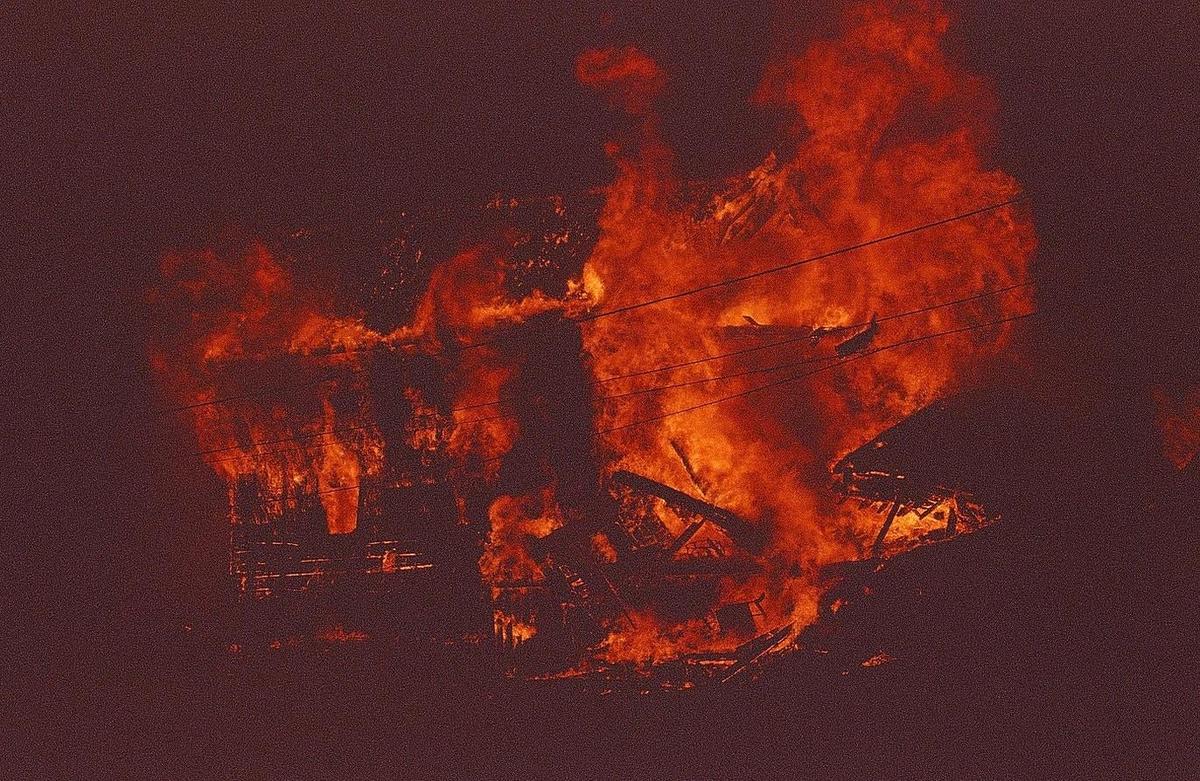 A building is engulfed in bright orange flames and smoke at night.
