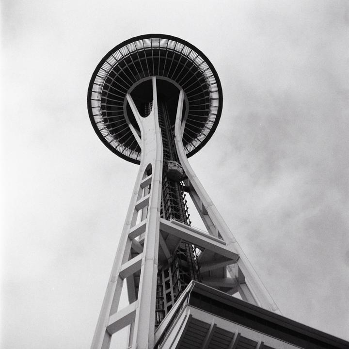 The Space Needle in Seattle is viewed from below against a cloudy sky.