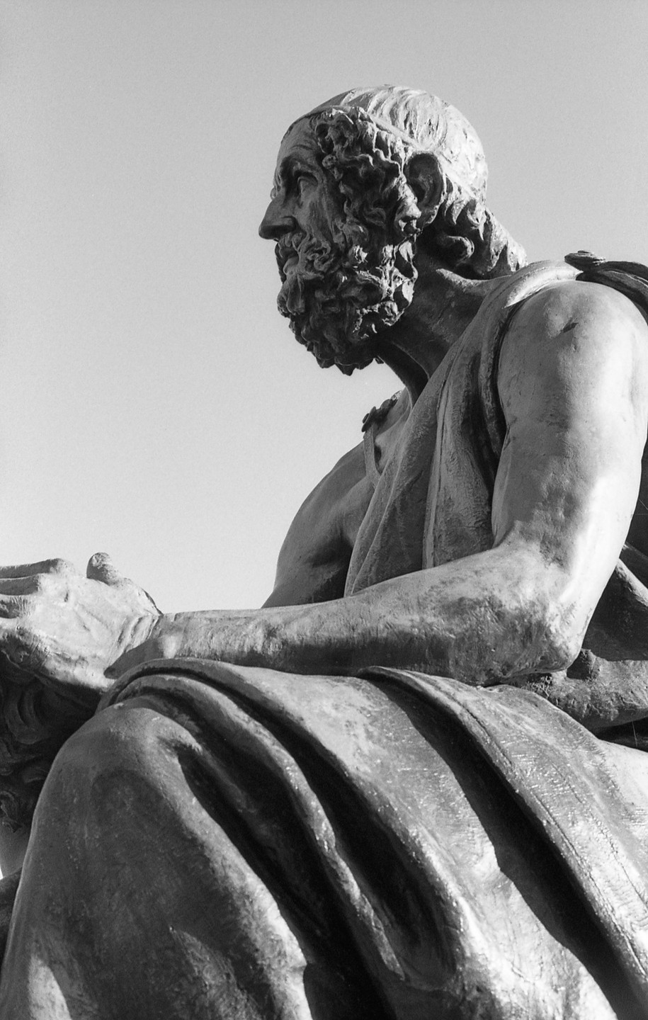 A statue of a bearded man in profile is shown from the chest up, with another statue visible in the lower left.