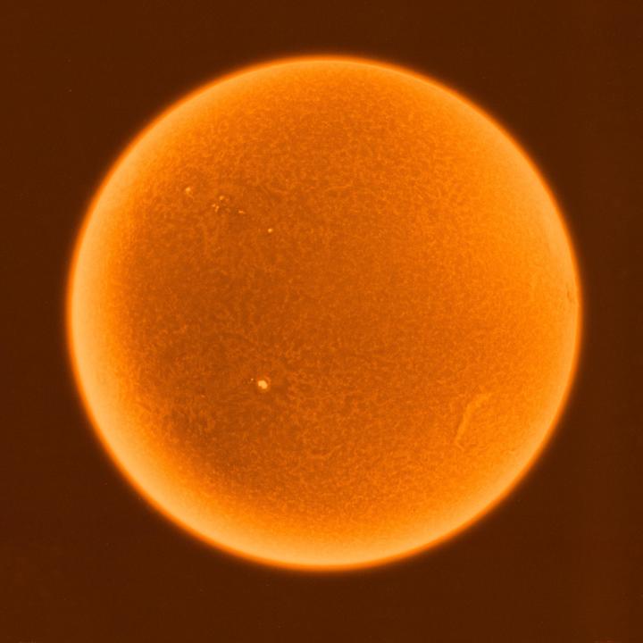 The surface of the sun is visible with several sunspots.