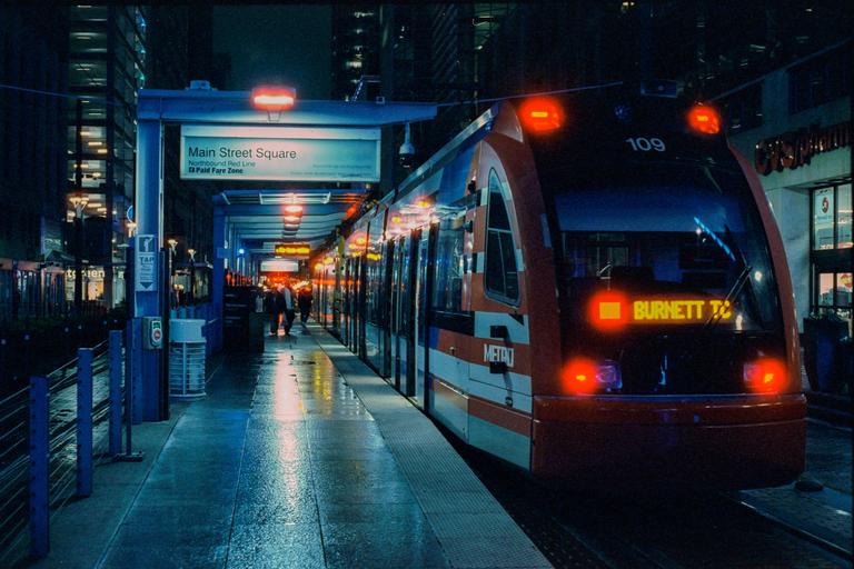 A red and white train is stopped at a station platform at night.