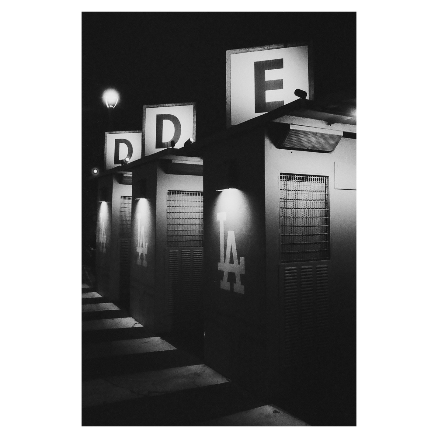 Three illuminated signs with the letters D, D, and E are visible above a row of structures with the LA Dodgers logo.
