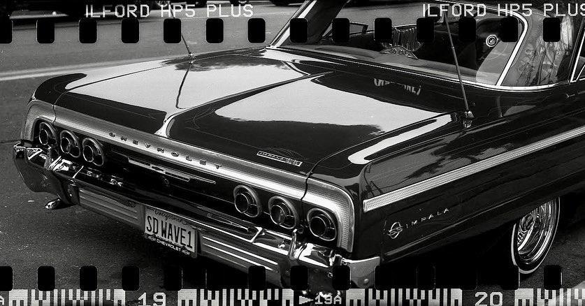 The rear of a Chevrolet Impala is visible, with its taillights and bumper reflecting light.