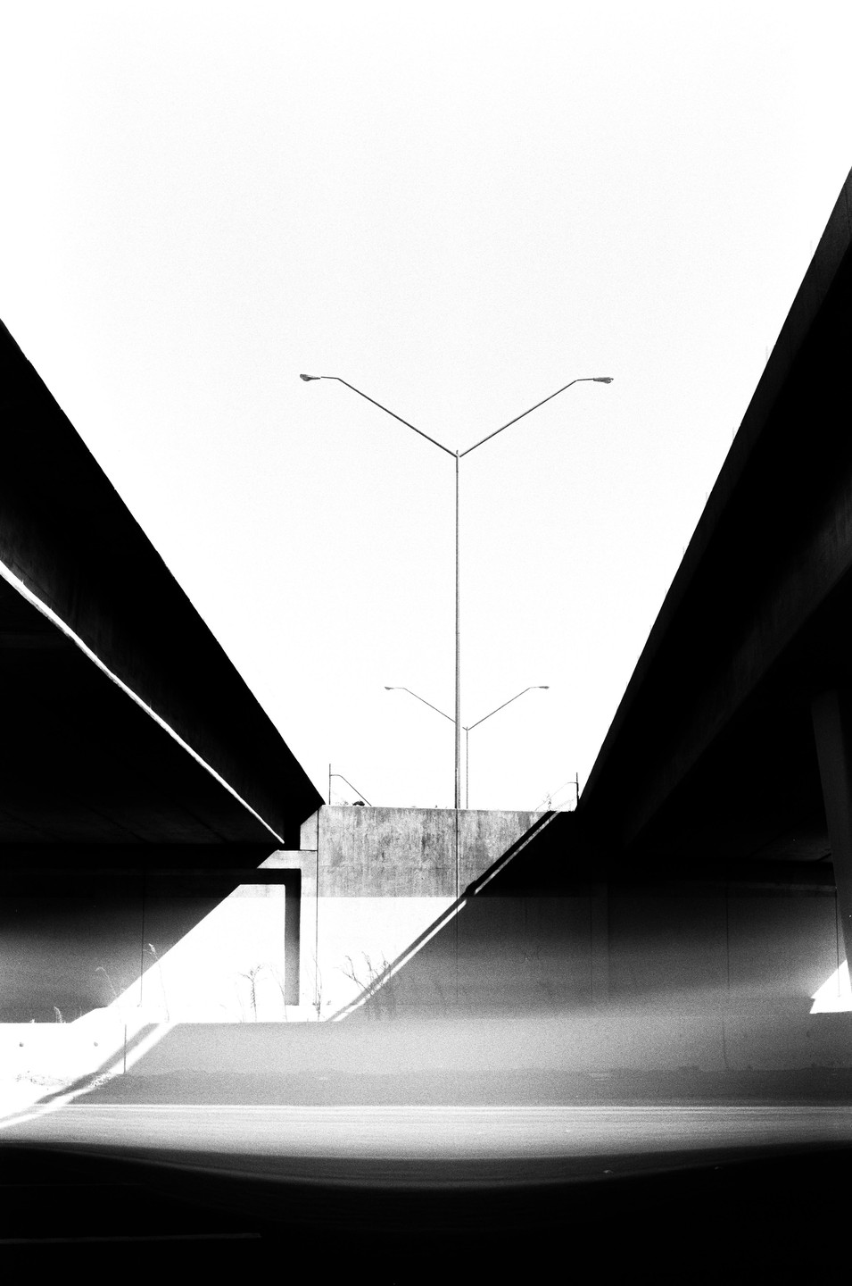 Two overpasses frame a concrete wall with streetlights and shadows.