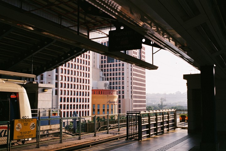 A train is stopped at a station platform with tall buildings in the background.