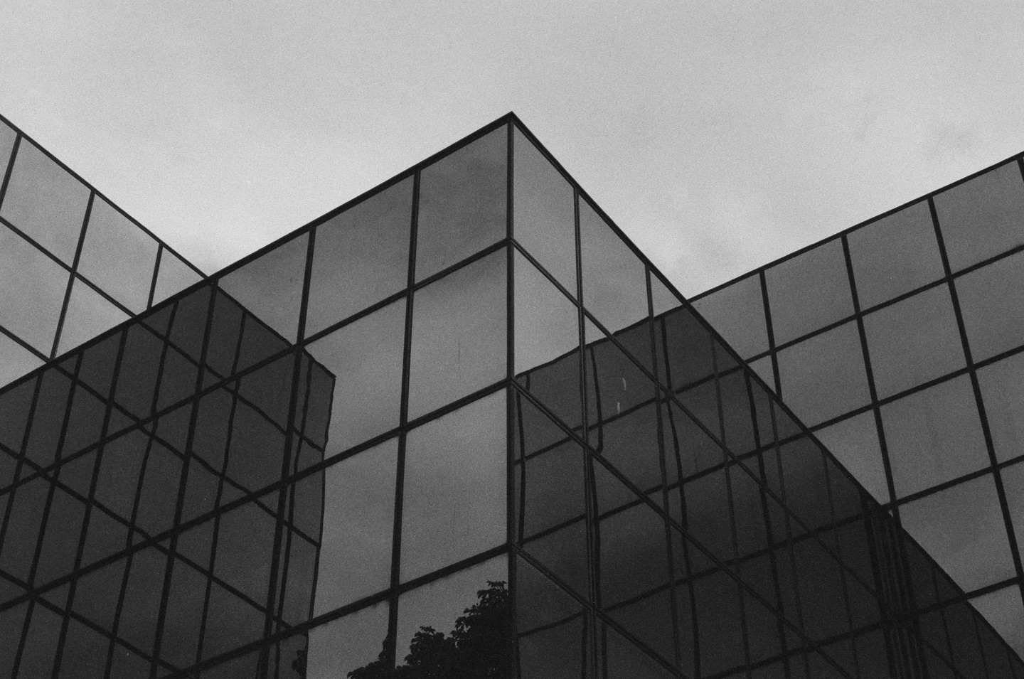 A modern building with a glass facade reflects the sky and surrounding structures.