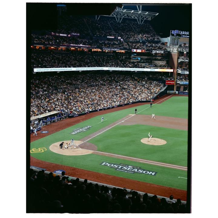 A baseball game is underway at night in a stadium filled with spectators.