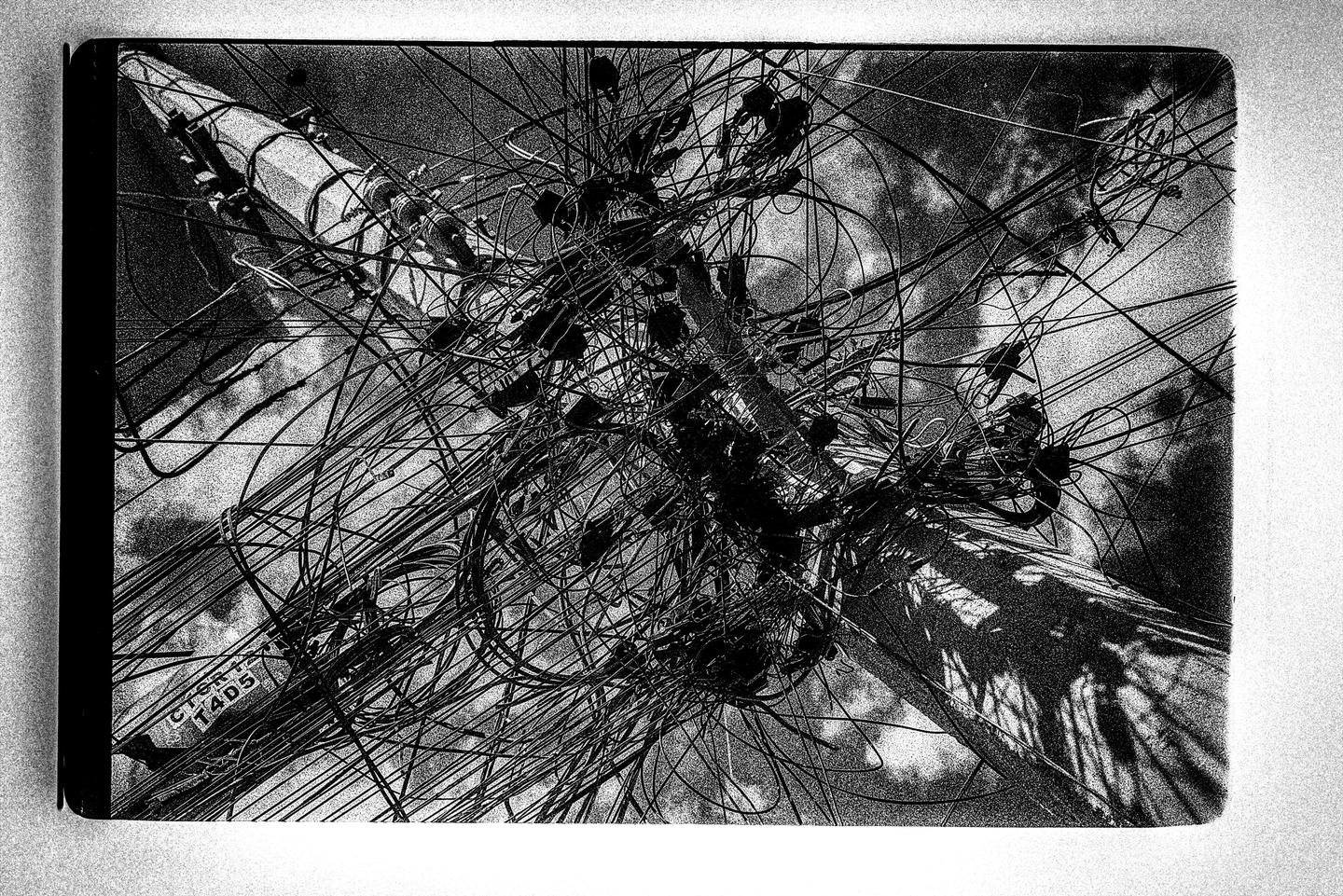 A utility pole is covered in a dense tangle of wires and cables.