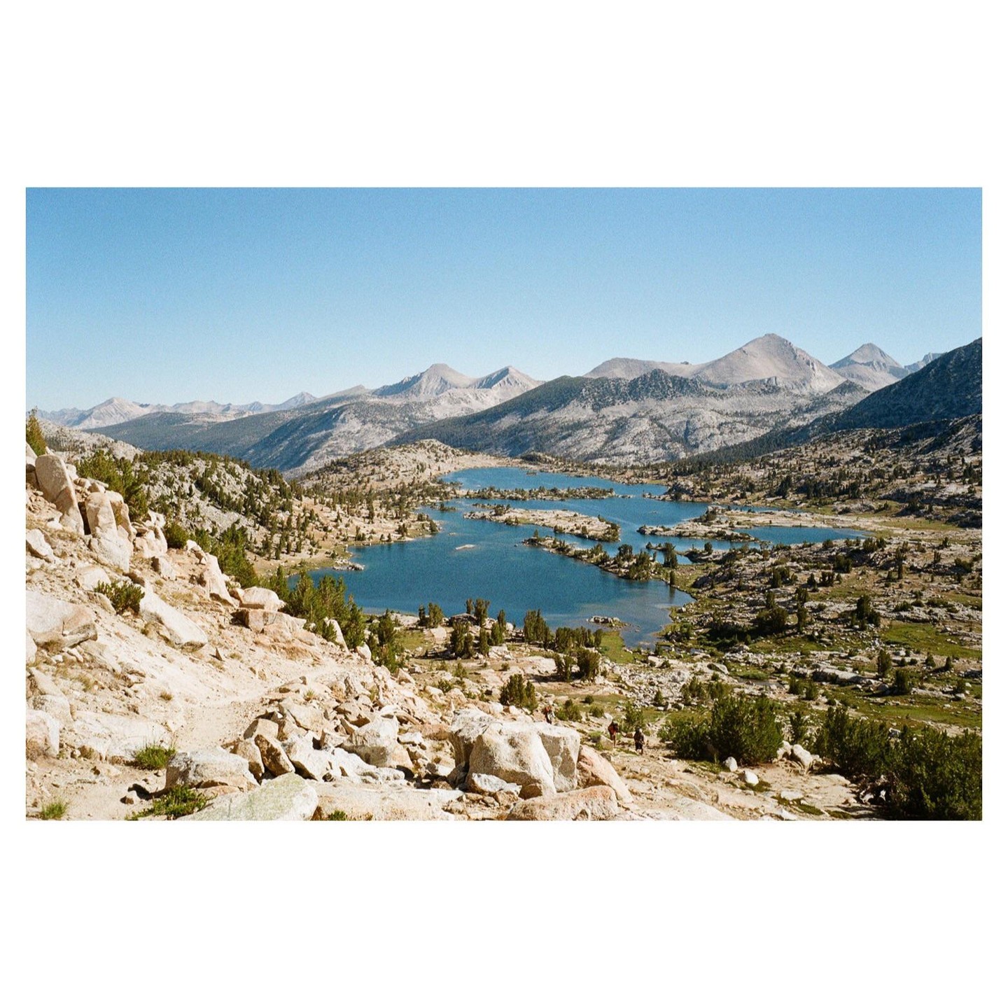 A wide shot shows a series of lakes nestled among mountains and rocky terrain.