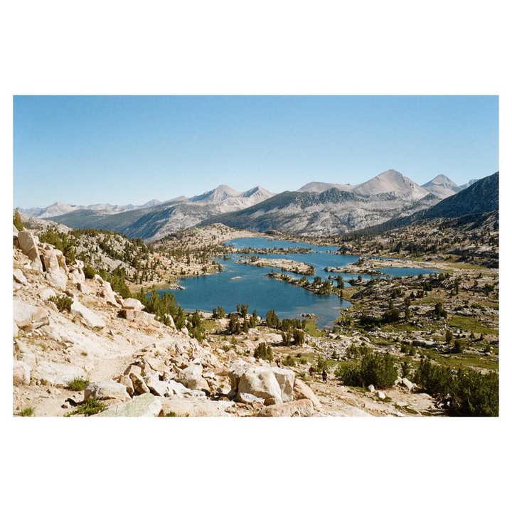 A wide shot shows a series of lakes nestled among mountains and rocky terrain.