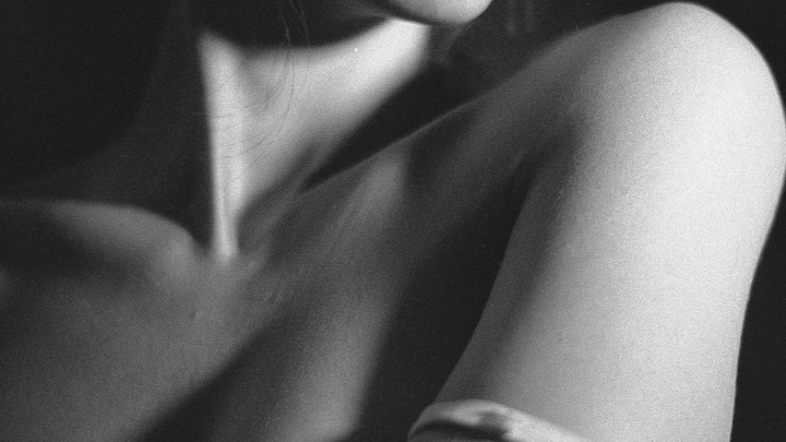 A woman's shoulder and neck are visible in a black and white close-up.