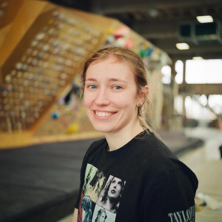 A woman smiles at the camera in a climbing gym.