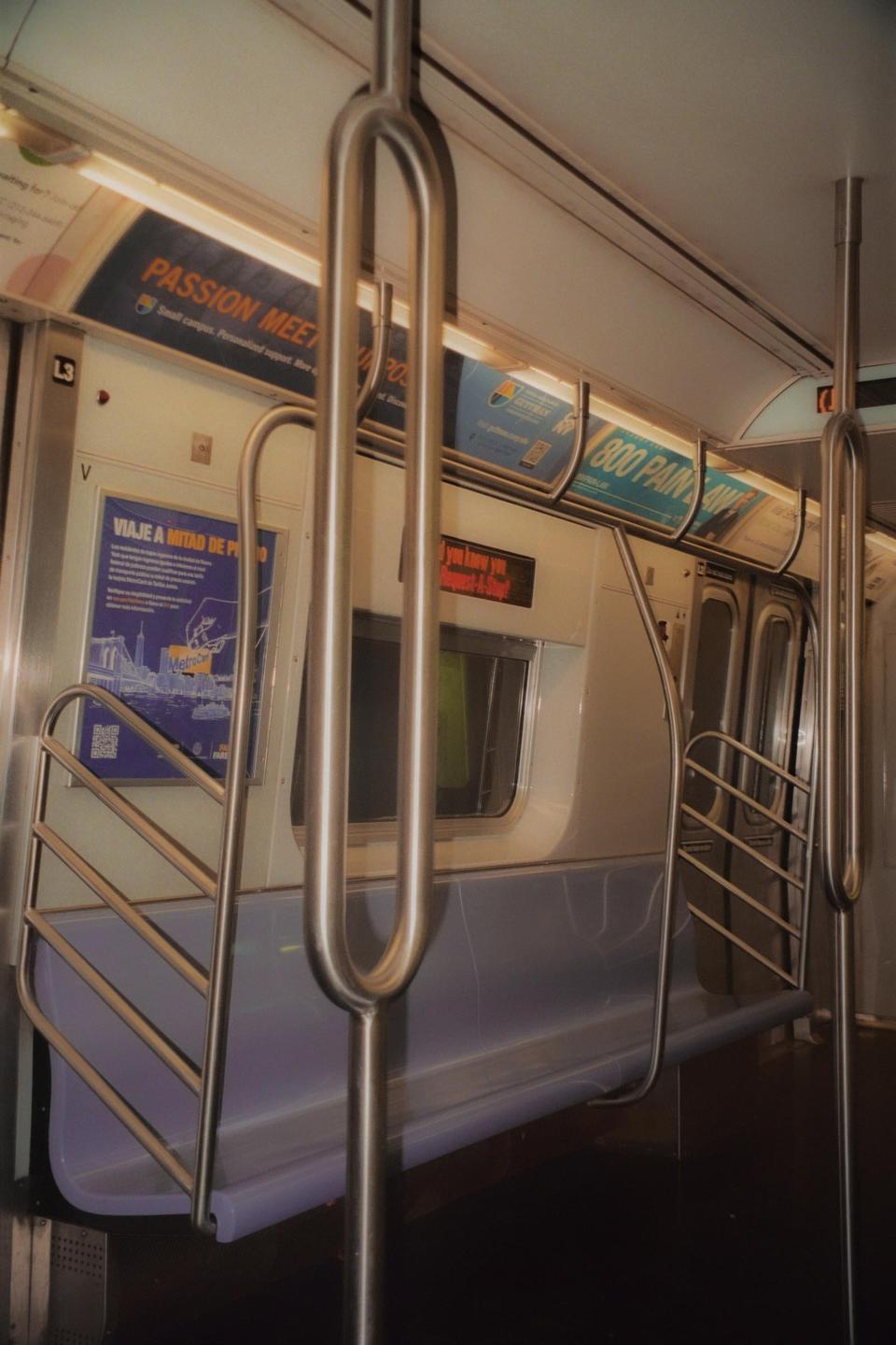 The interior of a subway car is visible with metal poles and advertisements on the walls.