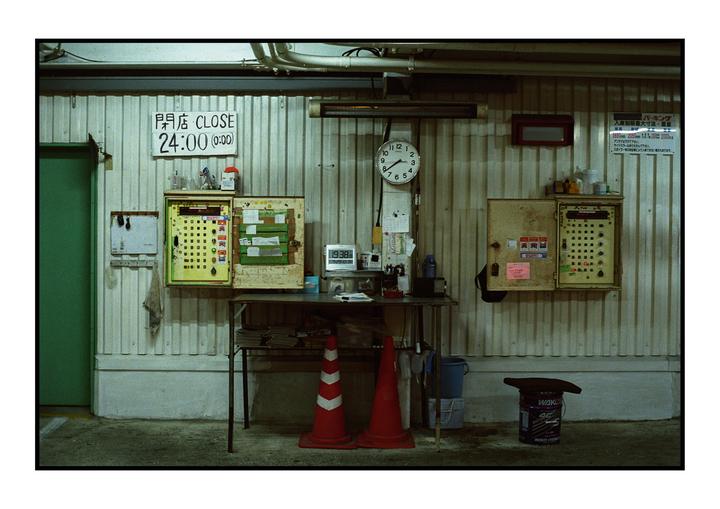A cluttered work area with a table, two traffic cones, and various items on a corrugated metal wall.