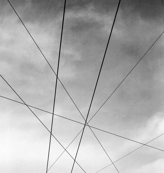 A black and white image shows a cloudy sky with multiple intersecting lines.