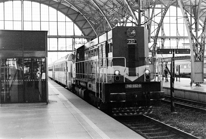 A train is stopped at a station platform under a large arched roof.