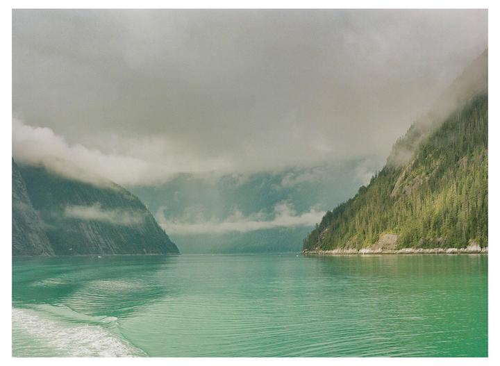 A body of water is surrounded by mountains covered in trees and fog.
