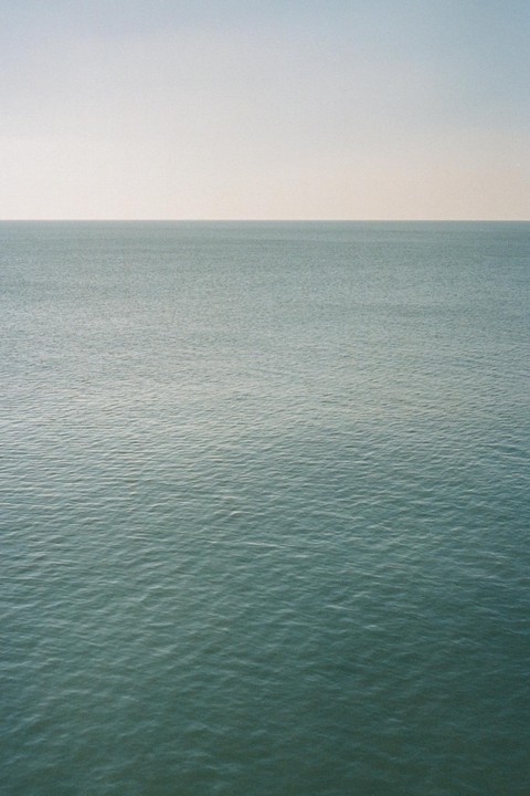 The calm ocean meets the horizon under a clear sky.