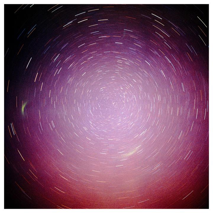 A long exposure photograph captures the circular trails of stars in the night sky.