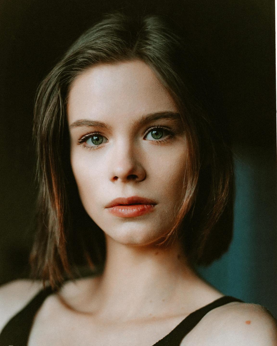 A woman with short hair and green eyes looks directly at the viewer.