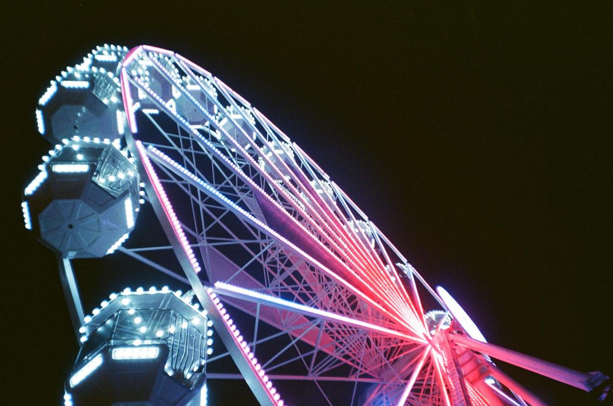 A ferris wheel with red and blue lights stands out against the night sky.