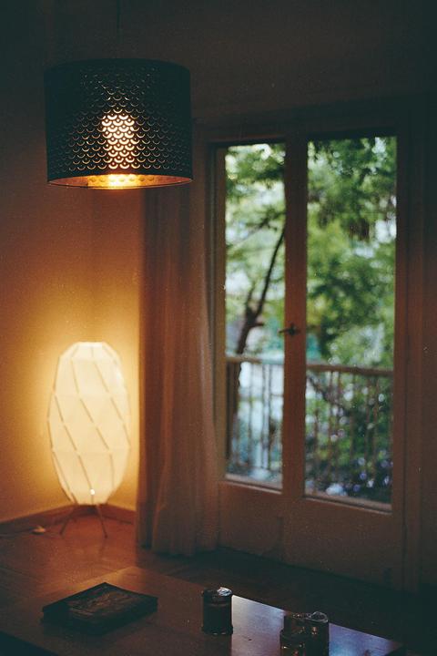 A room with two lamps and a glass door leading to a balcony with trees visible outside.
